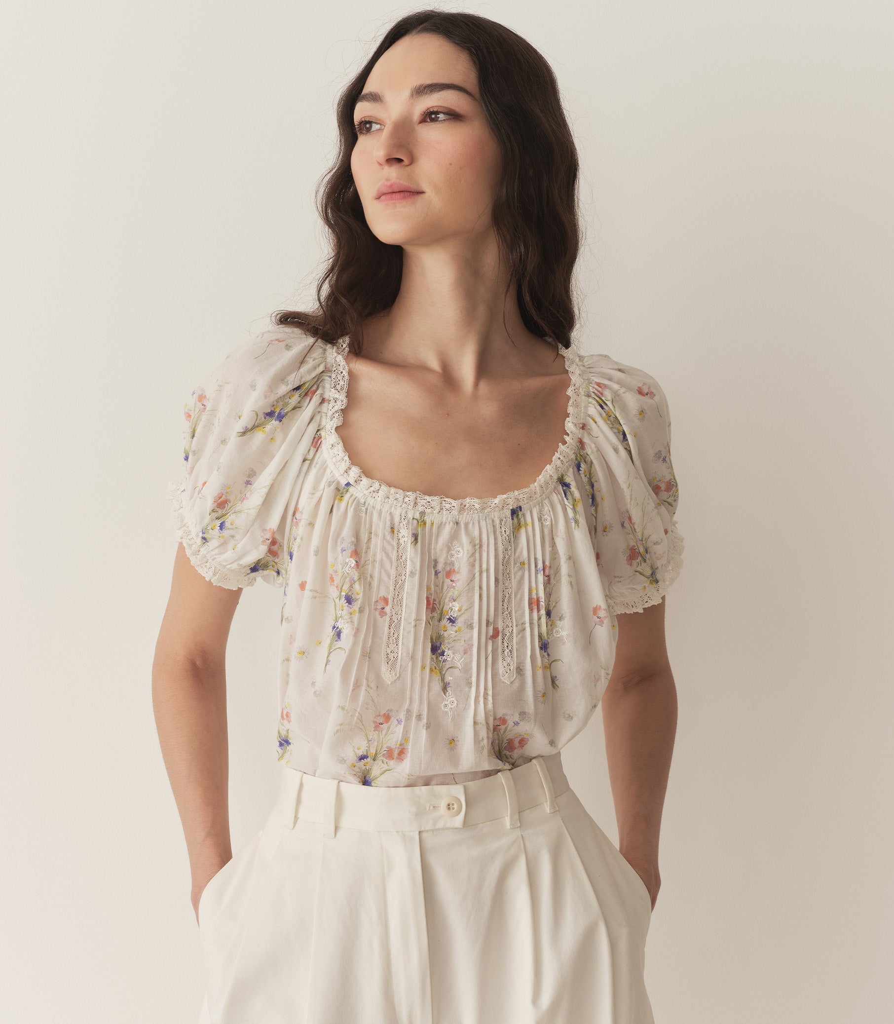 Bruna is wearing a white floral blouse with puff short sleeves. 1