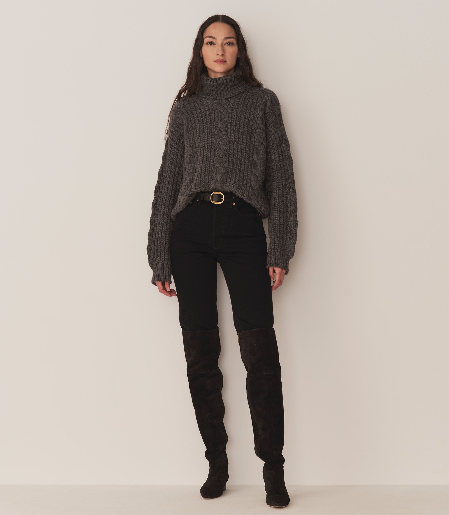 Person wearing a dark grey turtleneck sweater, black jeans, and black suede knee-length boots. 2