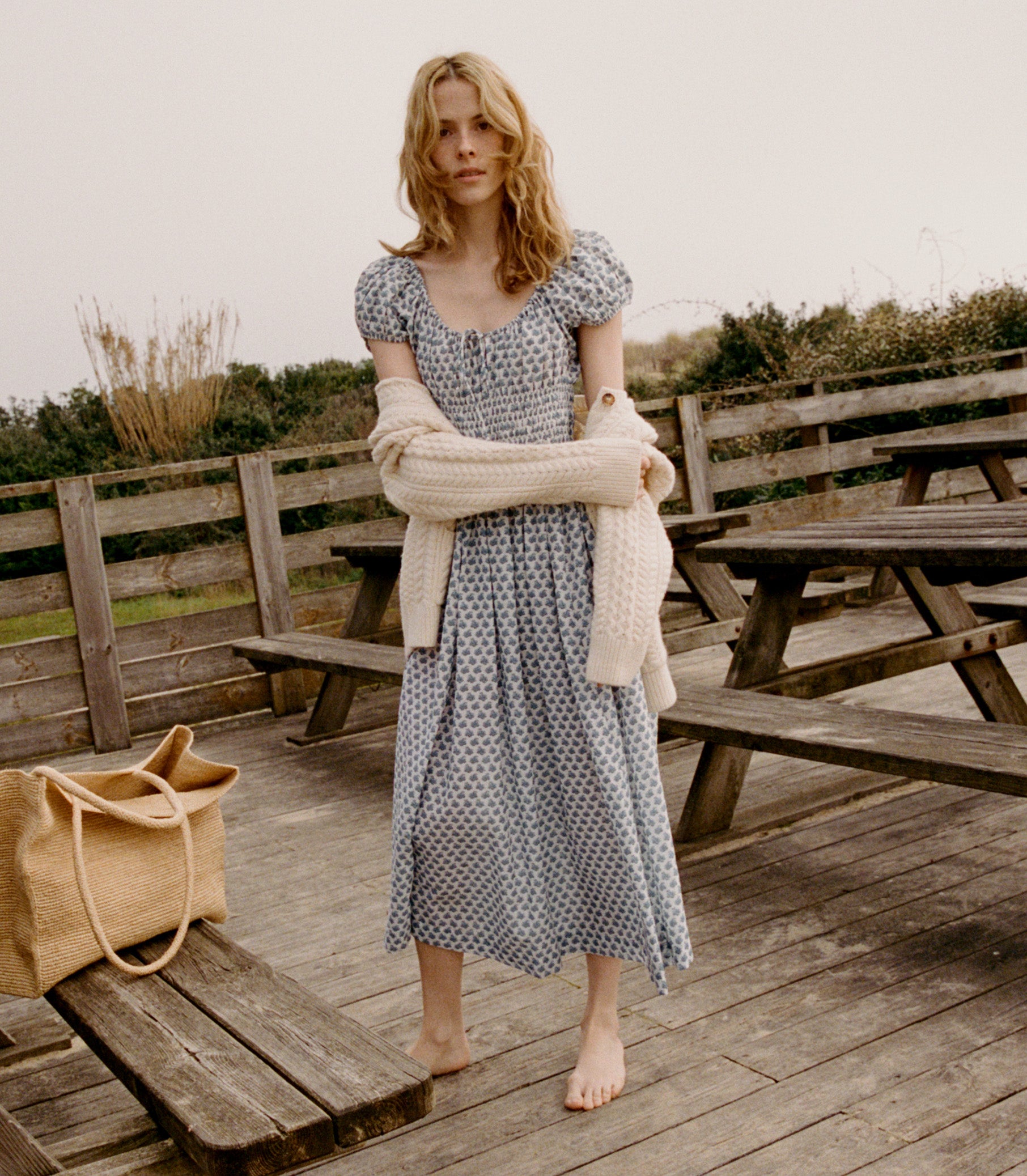 Alex wears the Quinn Dress in a blue dahlia ditsy print and a cream cardigan around her shoulders.